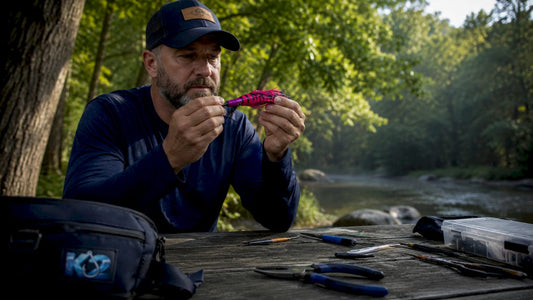 Angler inspecting handcrafted fishing lure outdoors